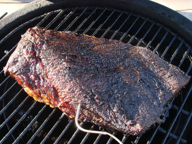 A smoked brisket being checked for internal temperature using a meat thermometer, demonstrating how to use a smoker.